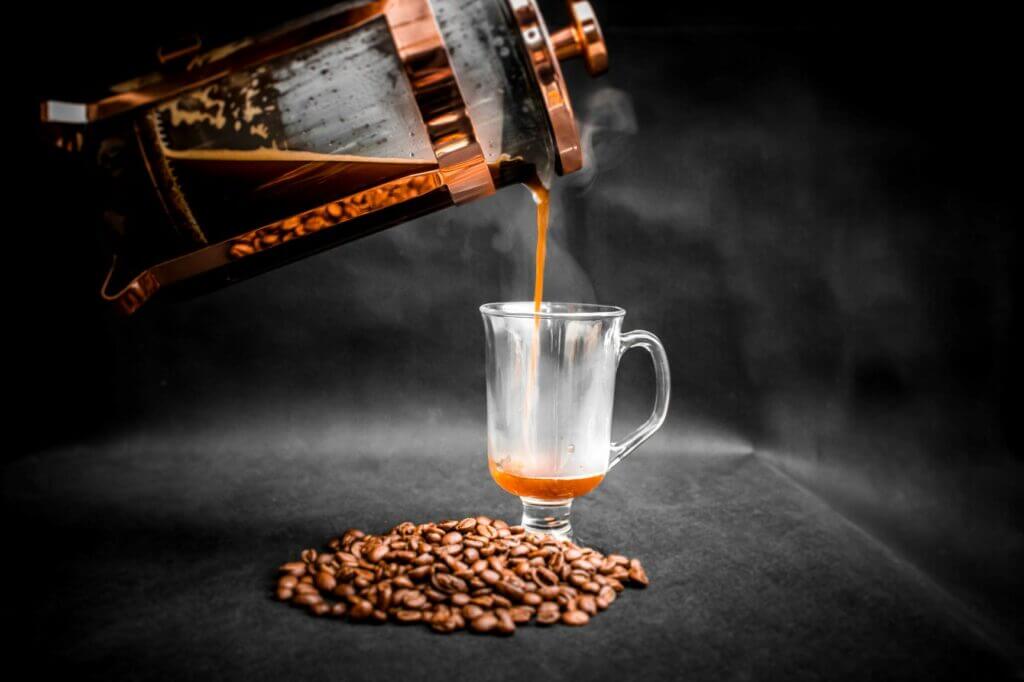 coffee-being-poured-from-french-press-into-elegant-glass